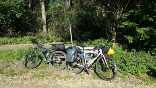 Our bikes in the sun at a break in front of a bench.