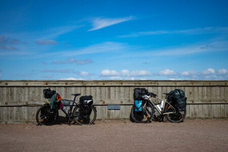 Two packed bikes in front of a wooden wall.