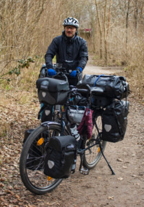 A man with two packed bicycles in a wood.