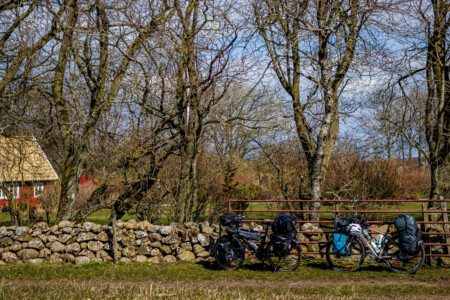Bikes resting along a fence and a stone wall near Båstad.